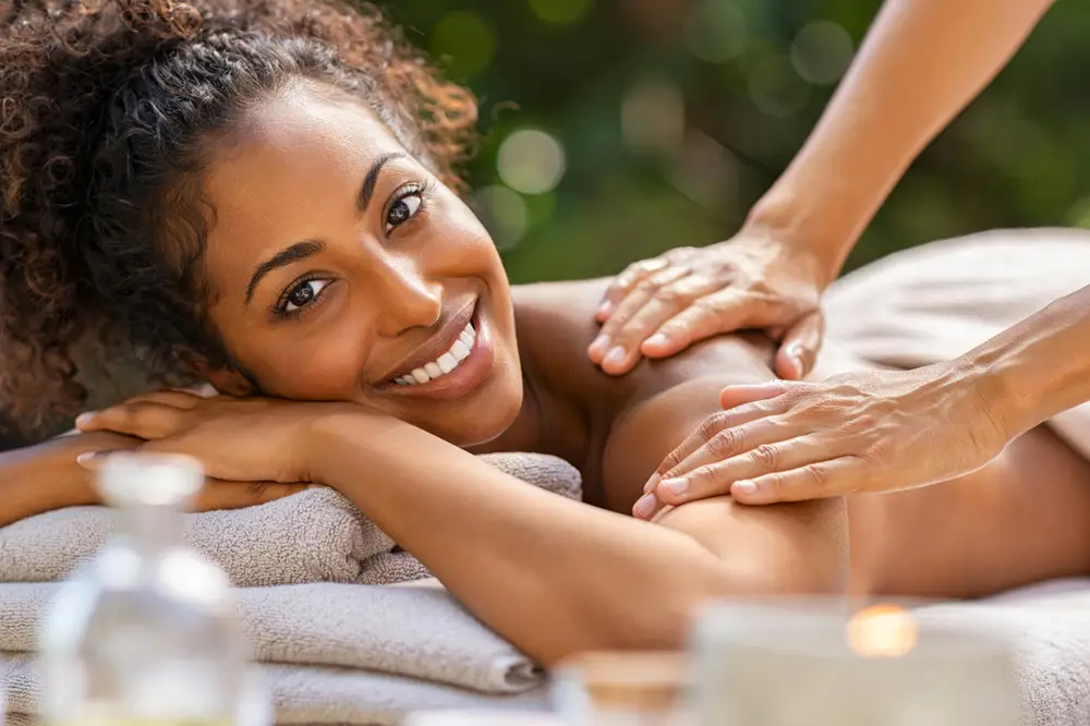 Woman smiling during a relaxing massage in an outdoor wellness setting