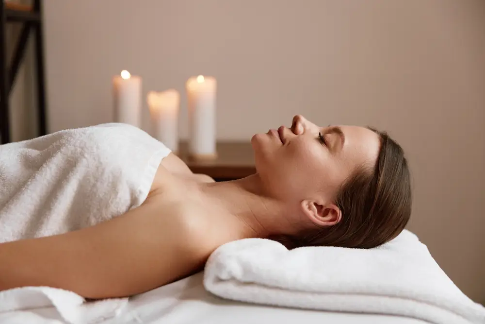 Woman lying peacefully in candlelit room before a massage session