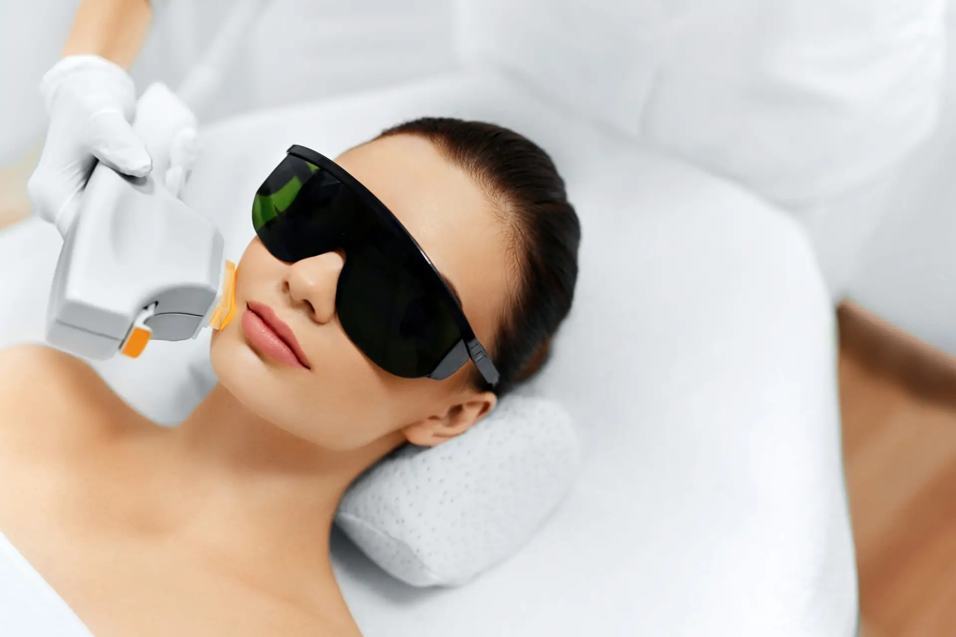 Woman receiving safe laser facial treatment with protective eyewear