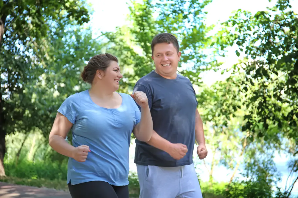 Happy couple walking outside after improving their health through a weight loss program